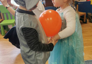 Dzieci tańcząc w parach trzymają brzuszkami balon